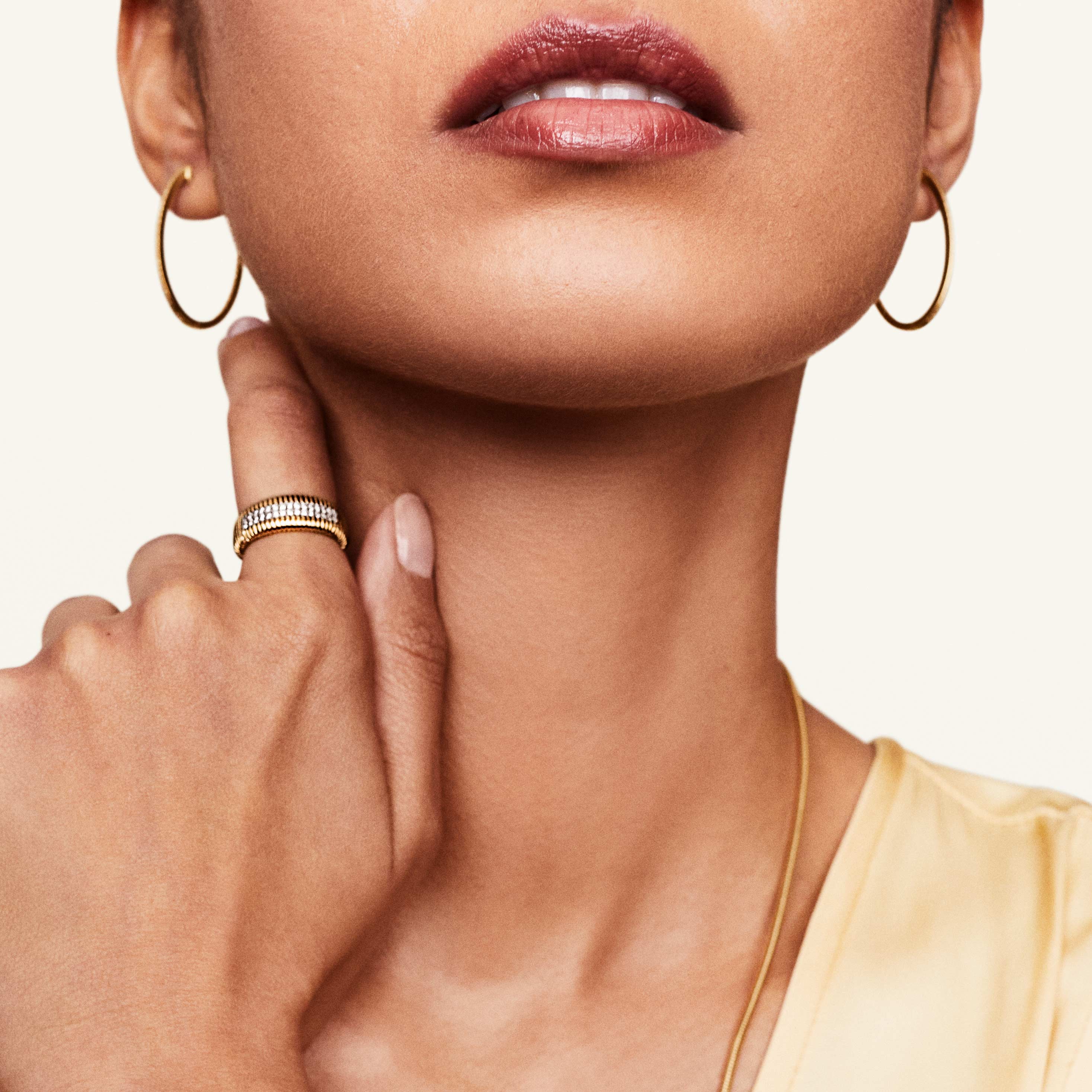 Model wearing pave diamond gold ring and gold hoops