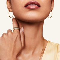 Model wearing pave diamond gold ring and gold hoops