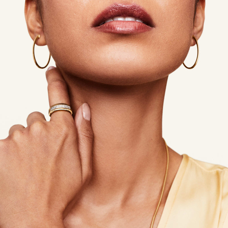 Model wearing pave diamond gold ring and gold hoops
