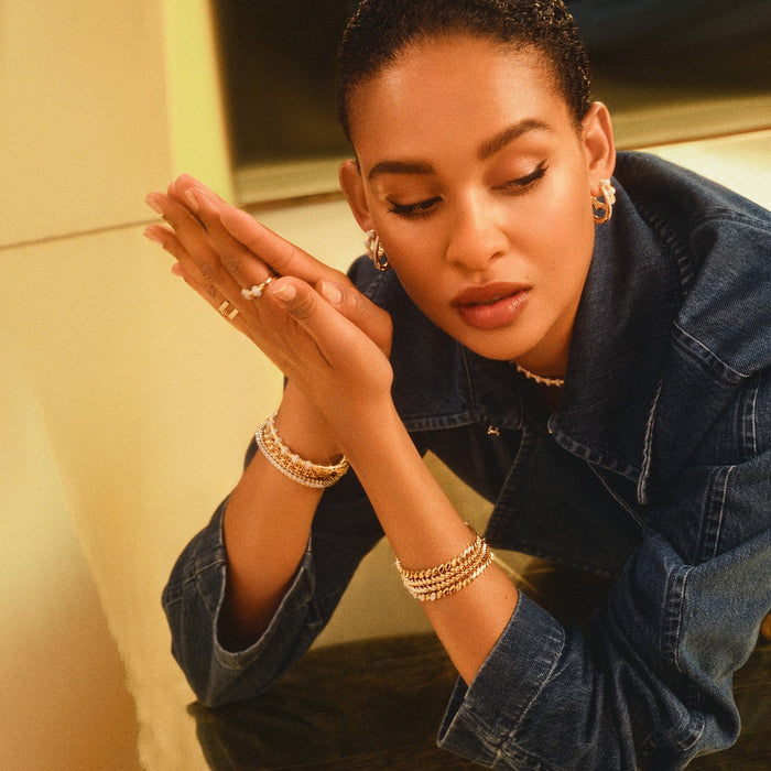 Model wearing several accessories including gold basketweave bracelet