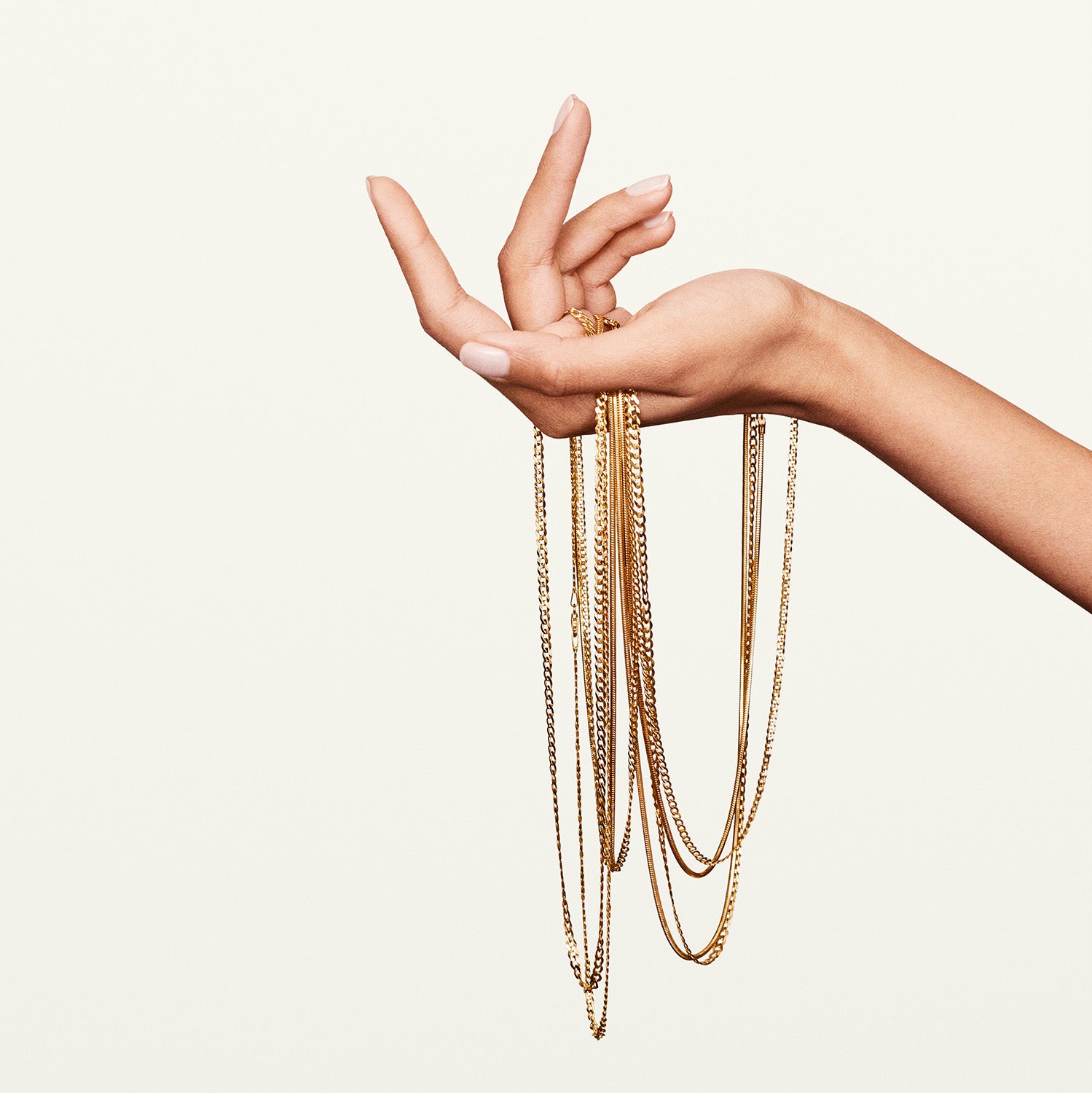 Yellow gold chains draped on a model's hand