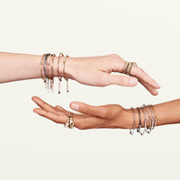 Shot of models' hands crossing over showcasing various bracelet with diamond bar