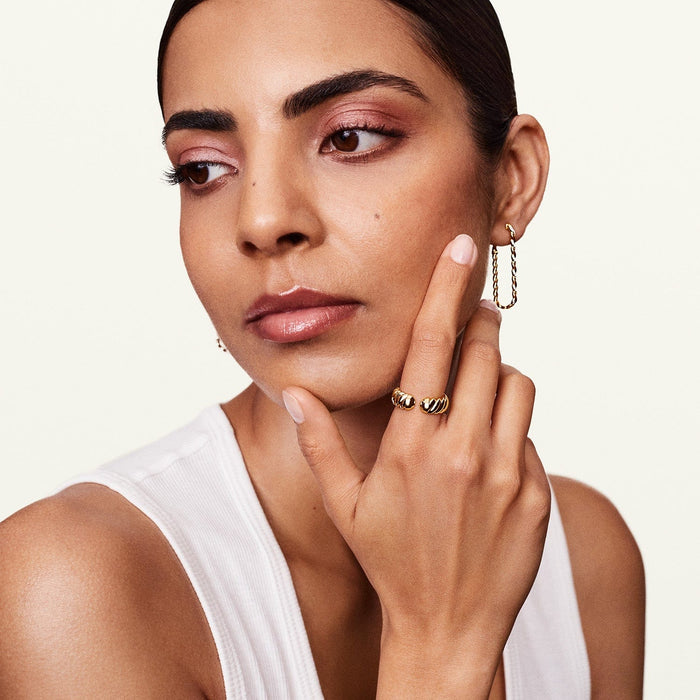 Shot of model wearing yellow gold diamond hoop earrings with matching jewelry 