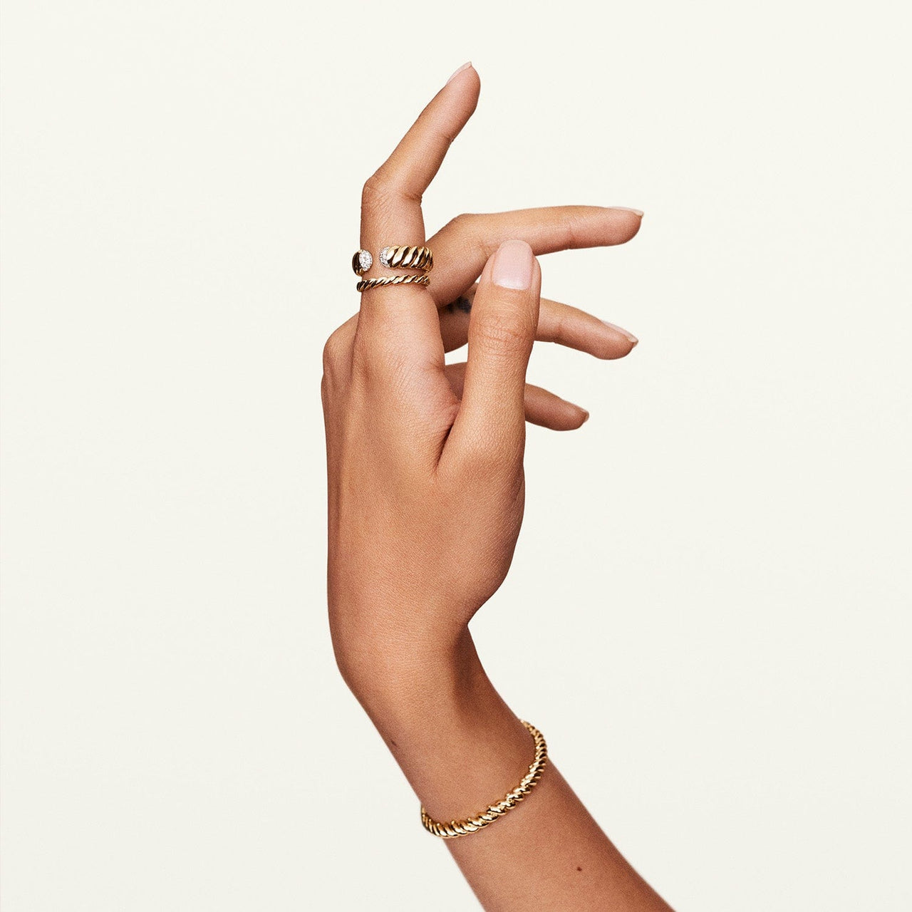 Shot of model wrist wearing gold infinity bracelet with matching jewelry 