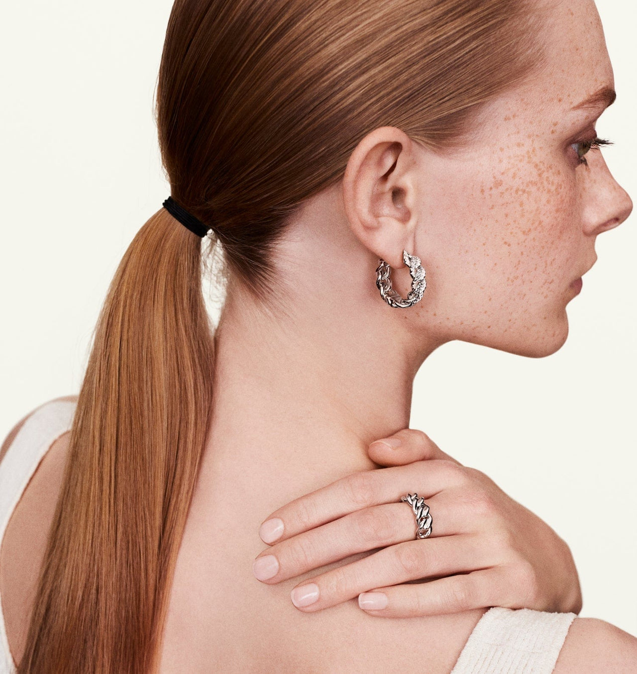Model wearing white gold chain diamond earrings with matching accessories