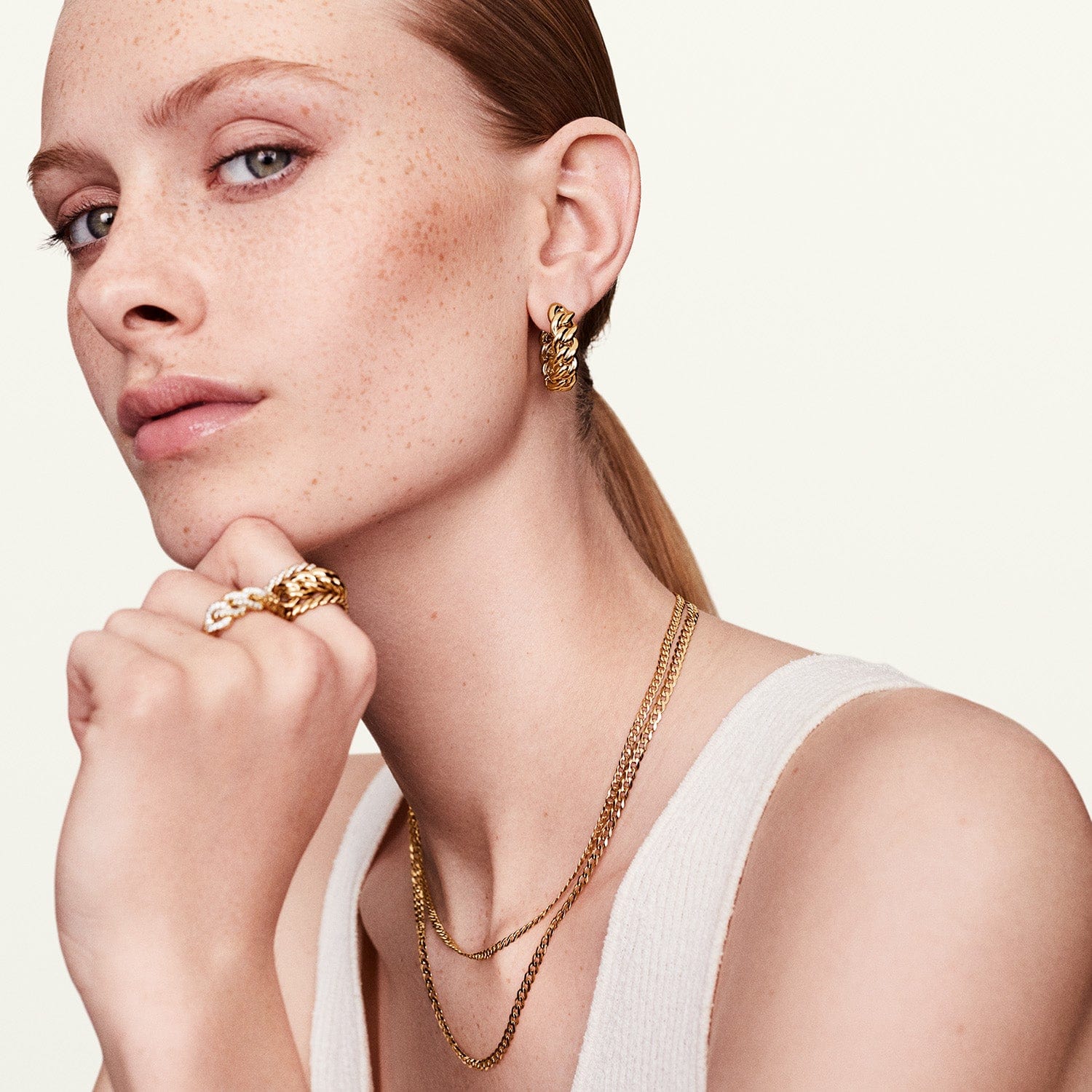 Model wearing gold chain hoop earrings with matching jewelry