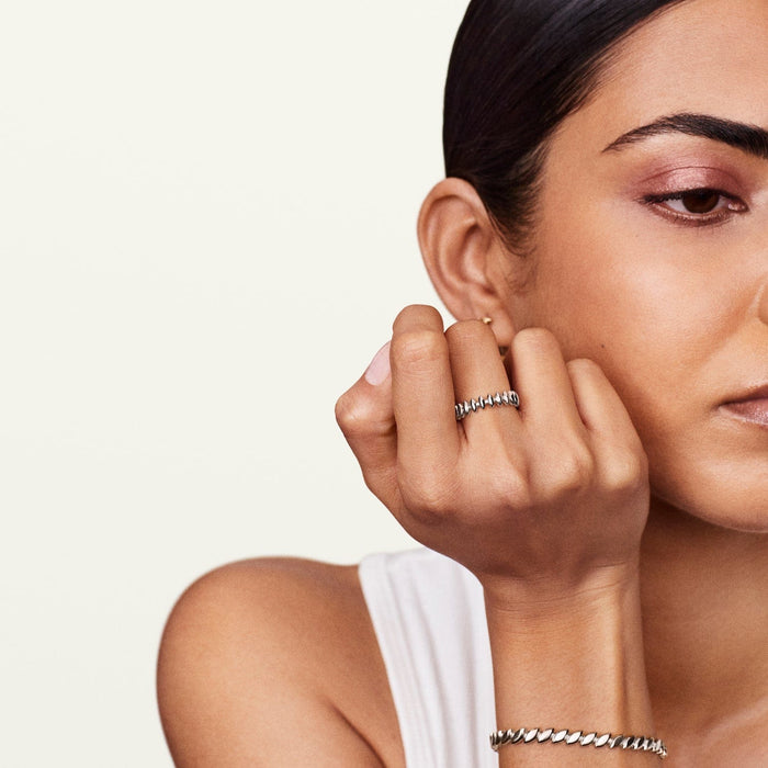 A person's hand wearing the Luna unique white gold ring, resembling a row of leaves.