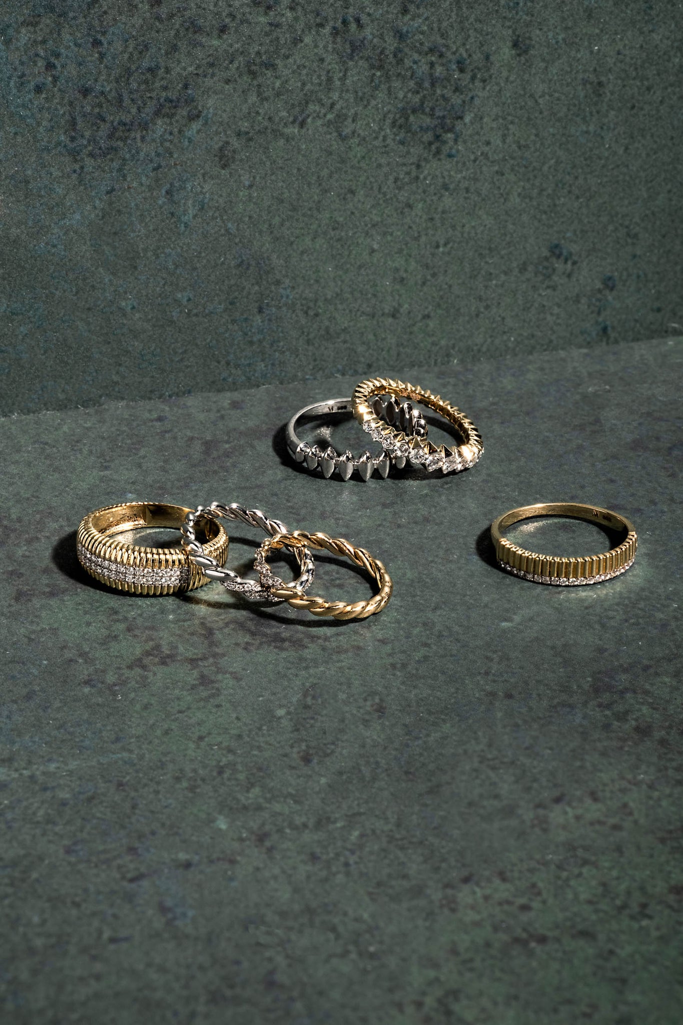  Gold stacking rings on a green textured background