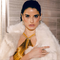 Woman wearing a gold top and white fur coat indoors wearing the YILAN yellow gold white Agate wrap necklace